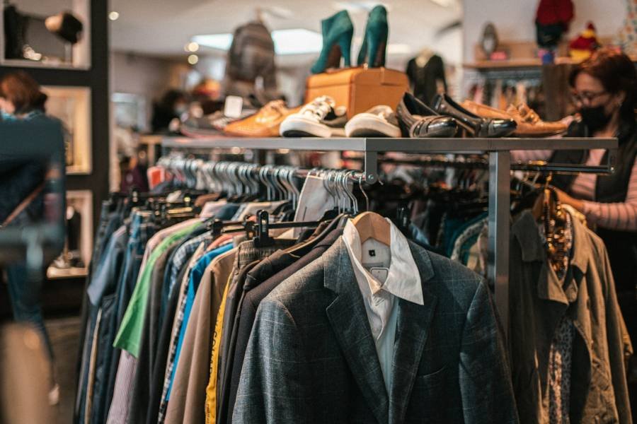 Rack of pre-loved clothes and shoes in a thrift store