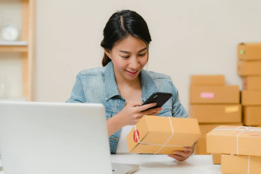 Seller checking an order on her phone next to parcels